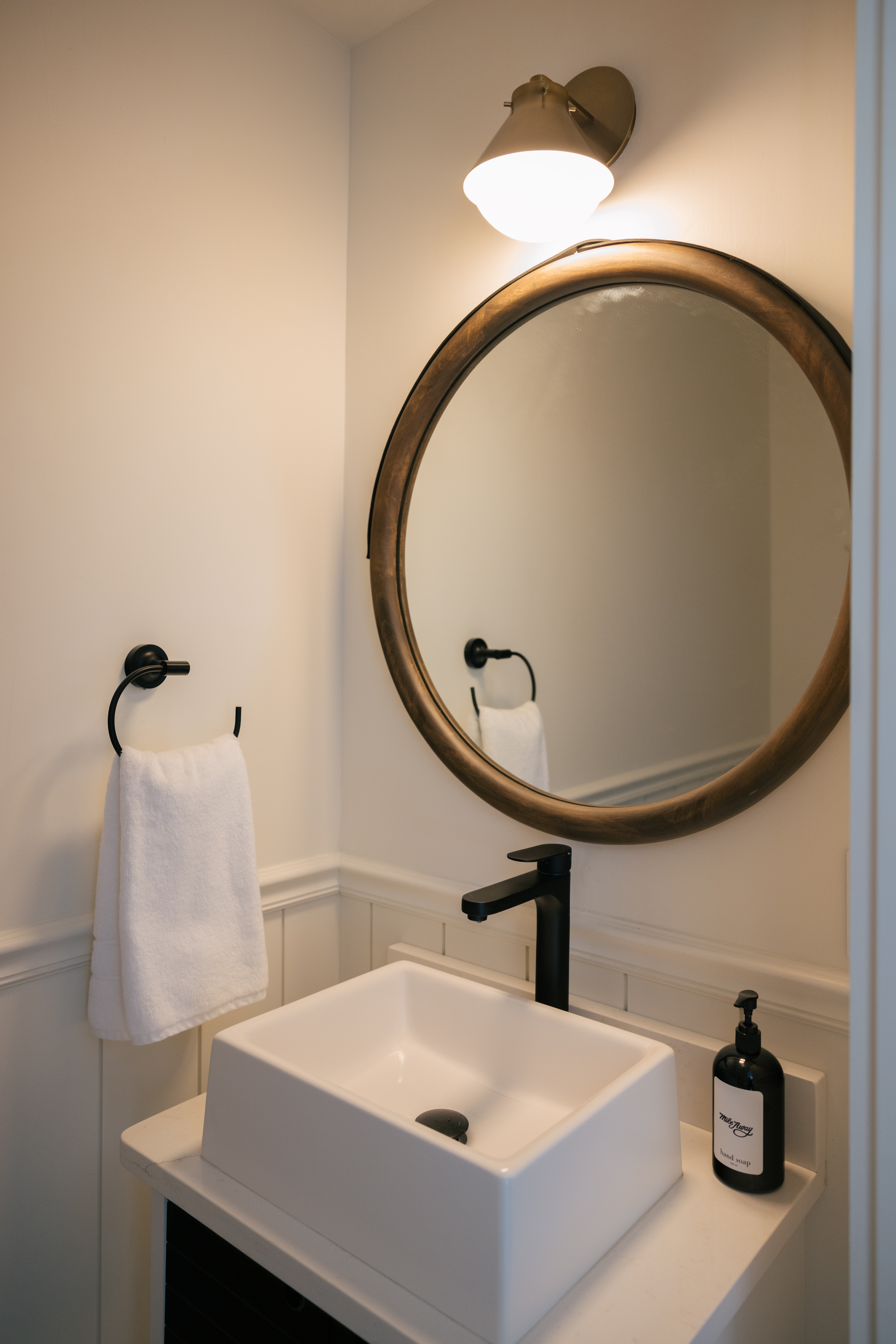 Powder room sink with round mirror and modern fixtures